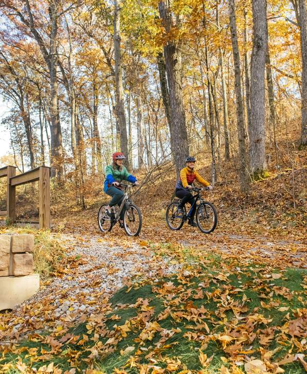 Mother and daughter mountain biking down a path in the fall