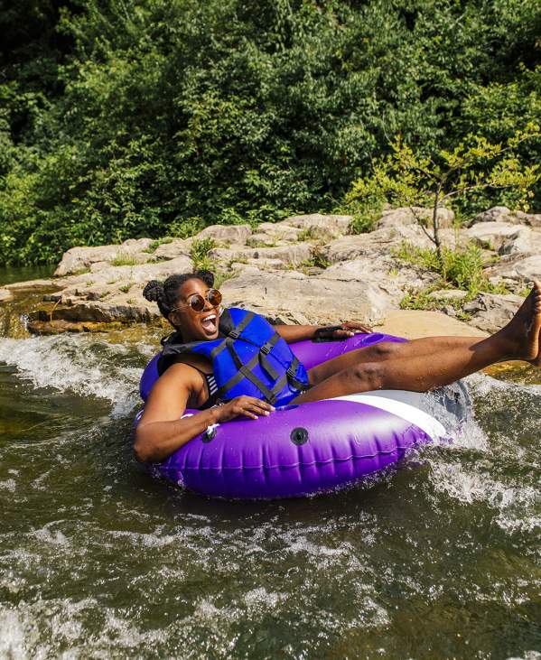 Woman in blue life jacket floating down the Huron River in a purple inner tube