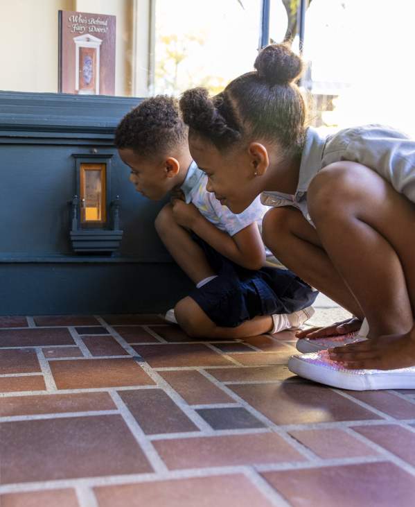 Two children kneeling down to look in a fairy door
