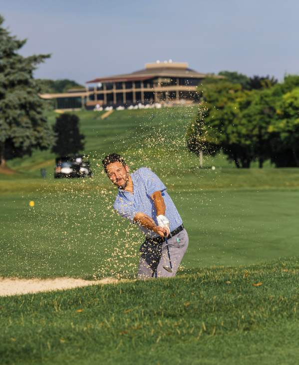 Man hitting golf shot out of sand