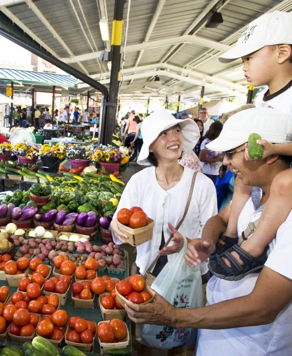 Family buying produce from a woman st the Ann Arbor Farmers Market