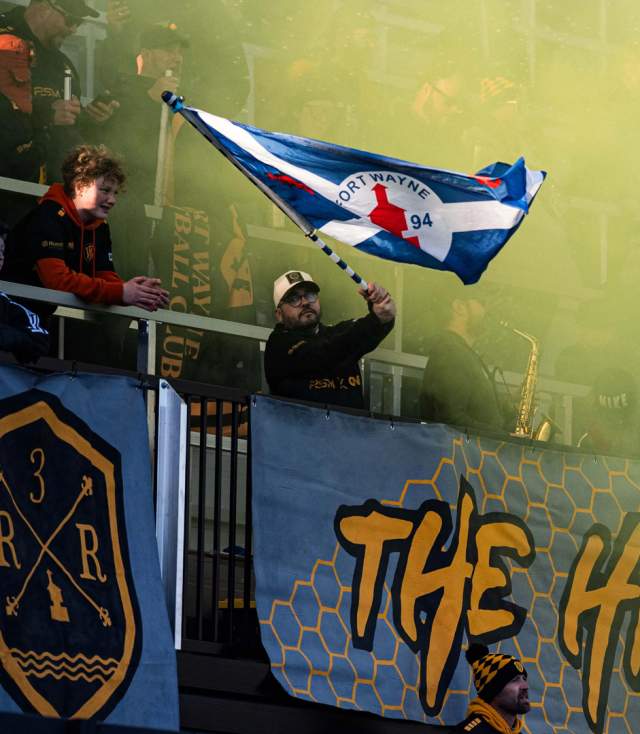 Fan waving a flag after a goal at a Fort Wayne Football Club match