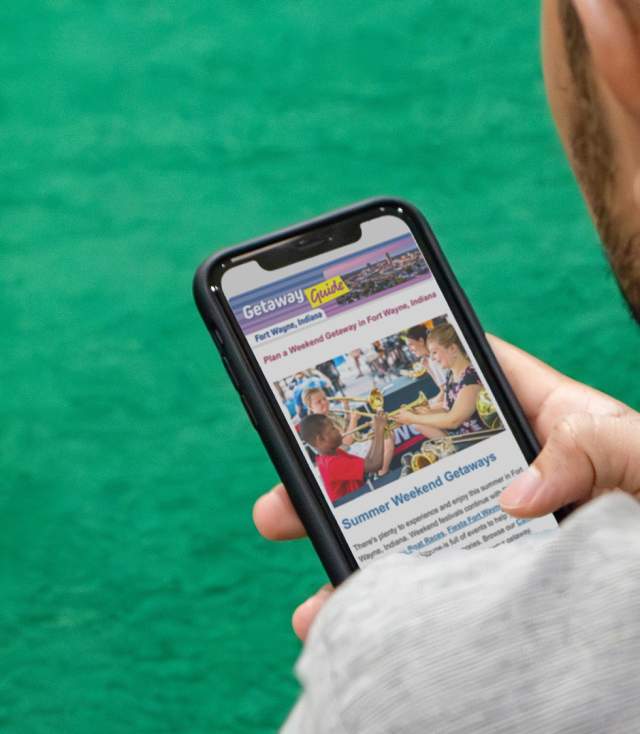 Man viewing Fort Wayne Getaway Guide email on mobile phone