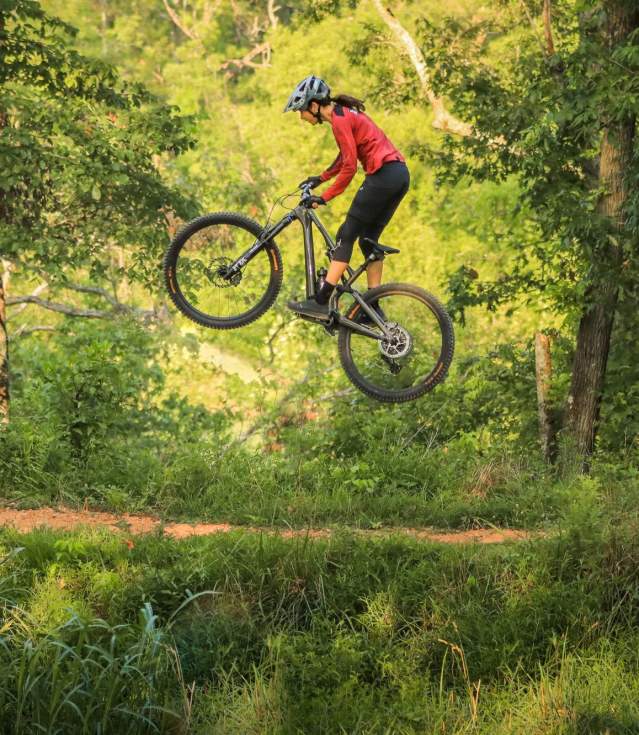 Anneke Beerten bikes through Bentonville, showcasing an outdoor art installation at The Momentary with vibrant sculptures against a scenic backdrop.