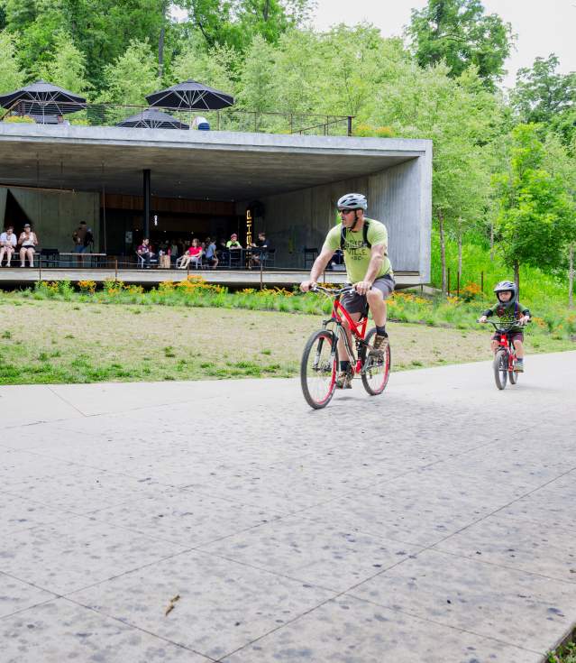 A family cycles on a sidewalk with Airship Coffeeshop in the background