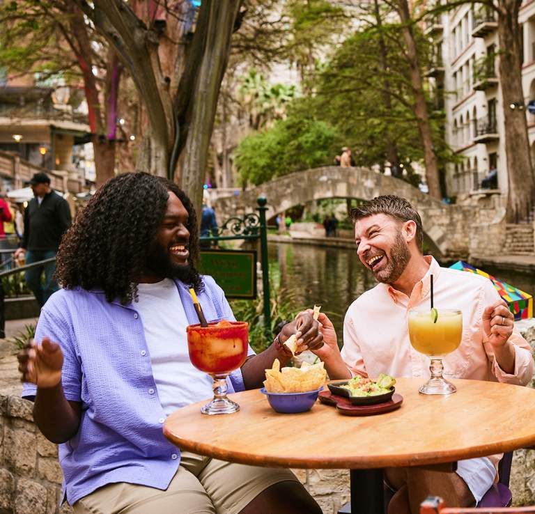 Two men on the River Walk enjoying chips and margaritas