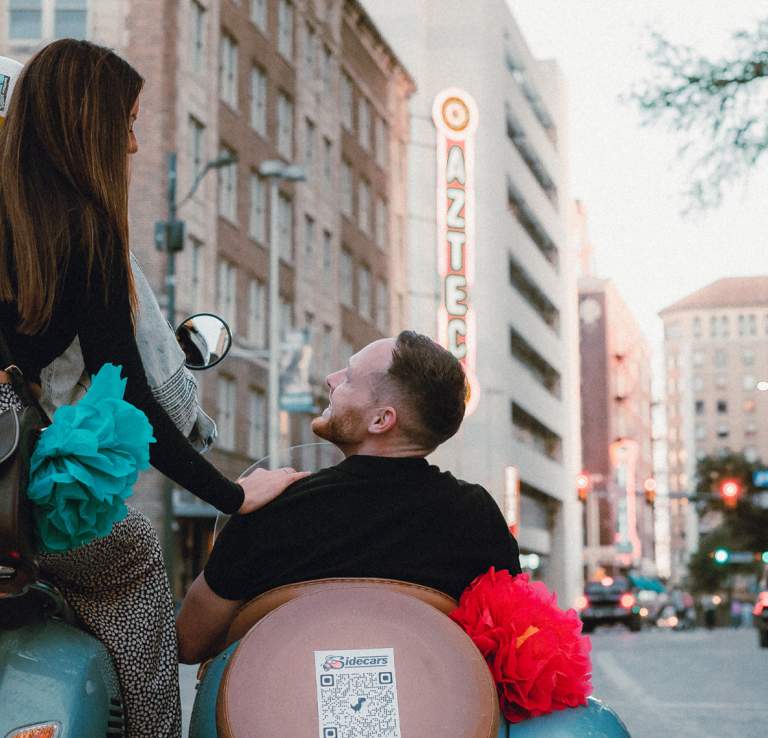 Man and woman on vespa and sidecar driving on San Antonio street