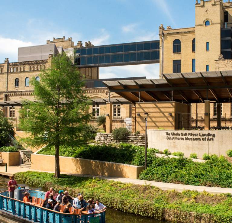 River barge drifting along river in front of San Antonio Museum of Art