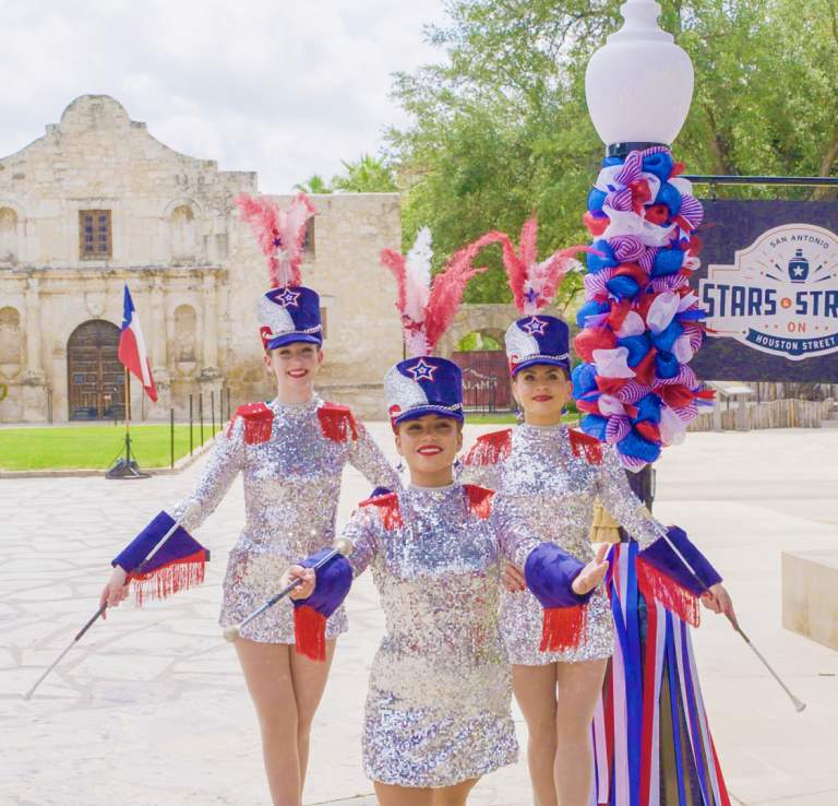 Three baton twirlers in front of the Alamo