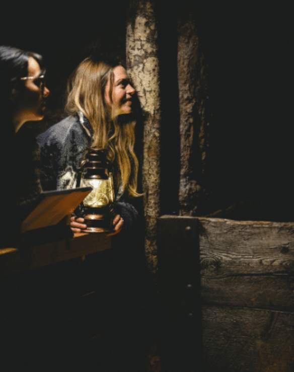 Two people with a lantern looking at a cave wall in the Nanaimo Museum.