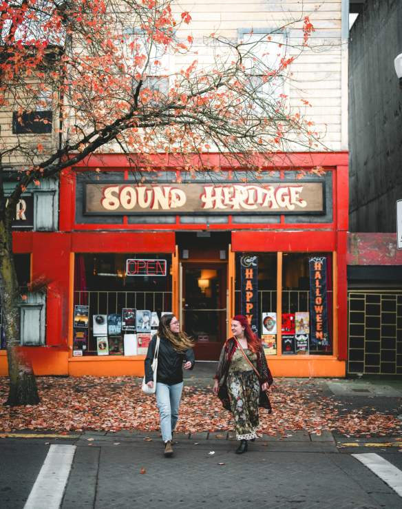 Two people walking outside of Sound Heritage on Victoria Crescent