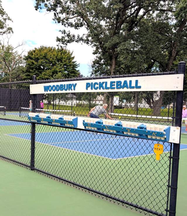 Pickleball players at Shawnee Park with a Woodbury Pickleball sign.