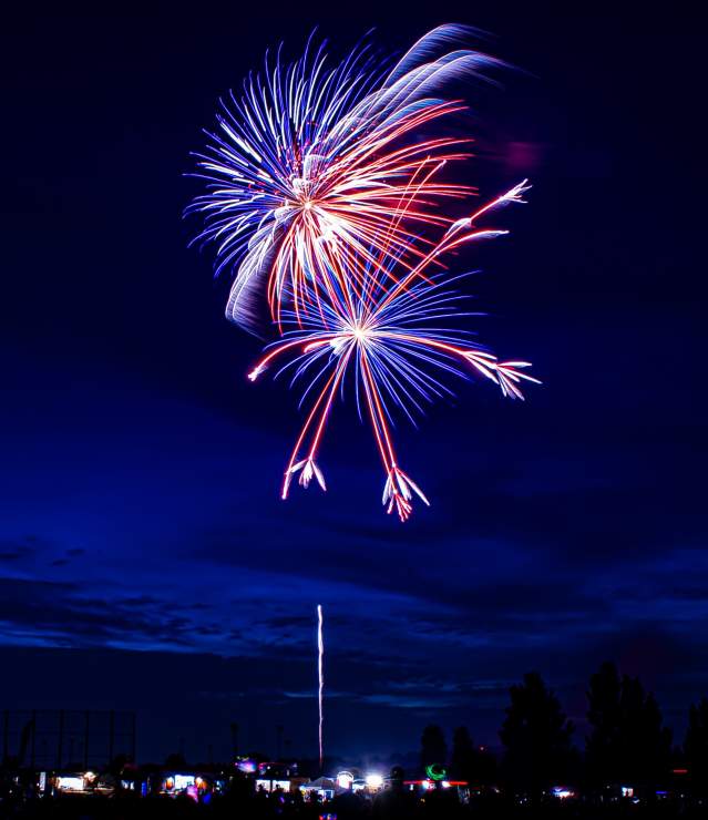 Red and blue fireworks in the dark blue sky during the 4th of July celebration