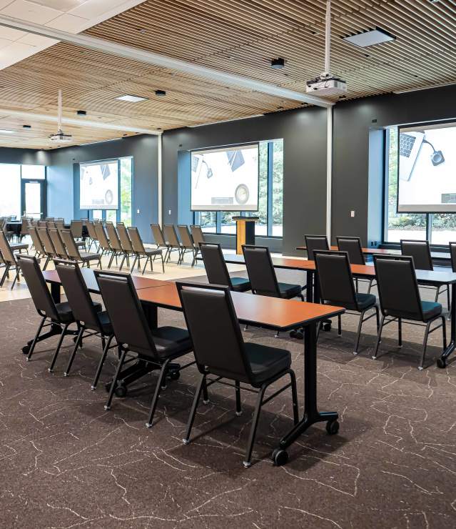 Meeting space shown with tables and chairs in Woodlands Room meeting space at Woodbury Central Park.
