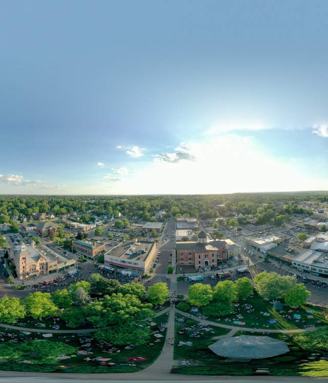 Drone photograph of the City with the sun peaking in the background on a blue sky day