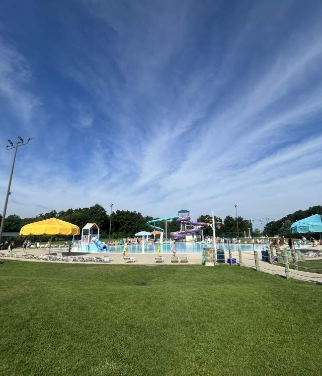 Grass giving way to the woodstock water works aquatic center with a bright blue sky