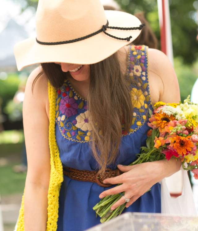 Woman in straw hat holding a bouquet of flowers at the Woodstock Farmers Market.