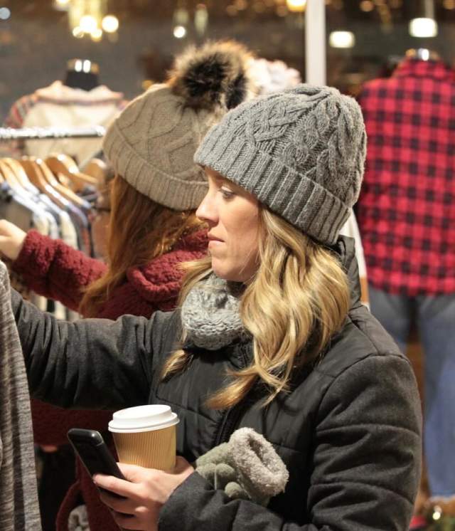 Woman holding a coffee wearing a knit hat shopping