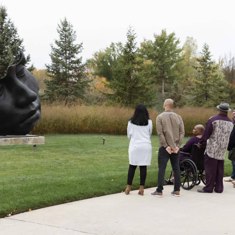 Visitors taking Igor Mitoraj's Light of the Moon - Further Out Frederik Meijer Gardens & Scuplture Park.