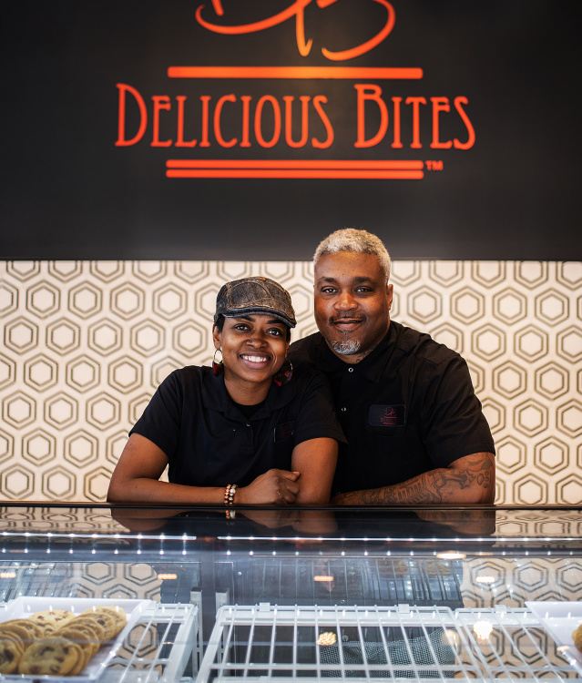 Delicious Bites Owners smiling behind treat counter