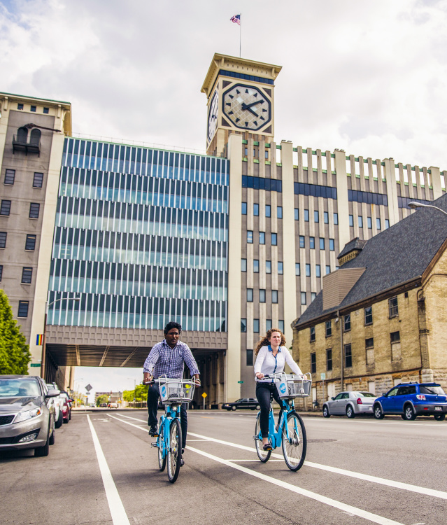two people using bublr bikes, biking under the clocktower