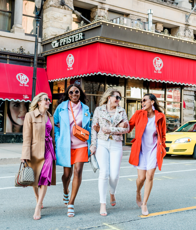 group of friends interlocking arms and walking in front of the Pfister Hotel