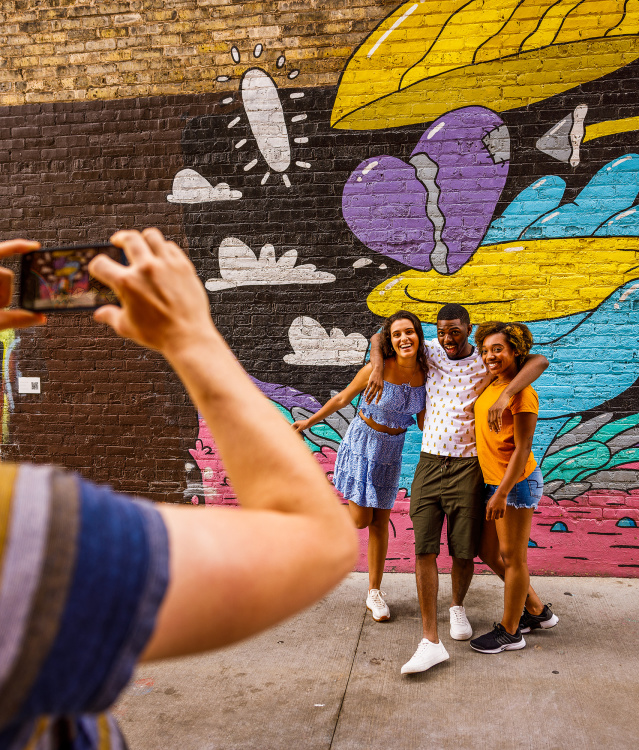 friends taking a picture in front of a colorful mural