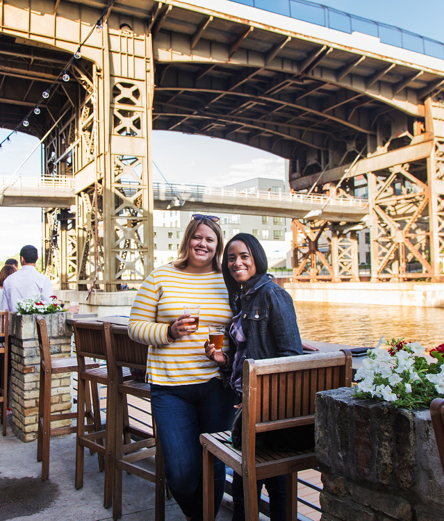 two friends smiling on riverwalk by Lakefront Brewery