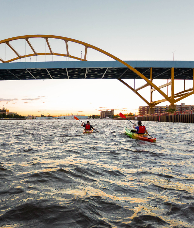 two kayakers kayaking under the Hoan Bridge