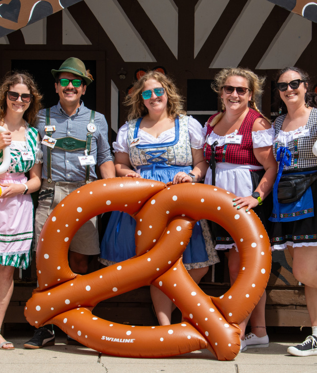 5 people with inflatable pretzel and beer props in German attire.