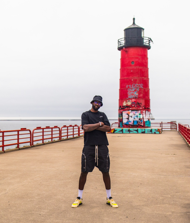 Bobby Portis posed in an all black outfit in front of a red lighthouse on Lake Michigan