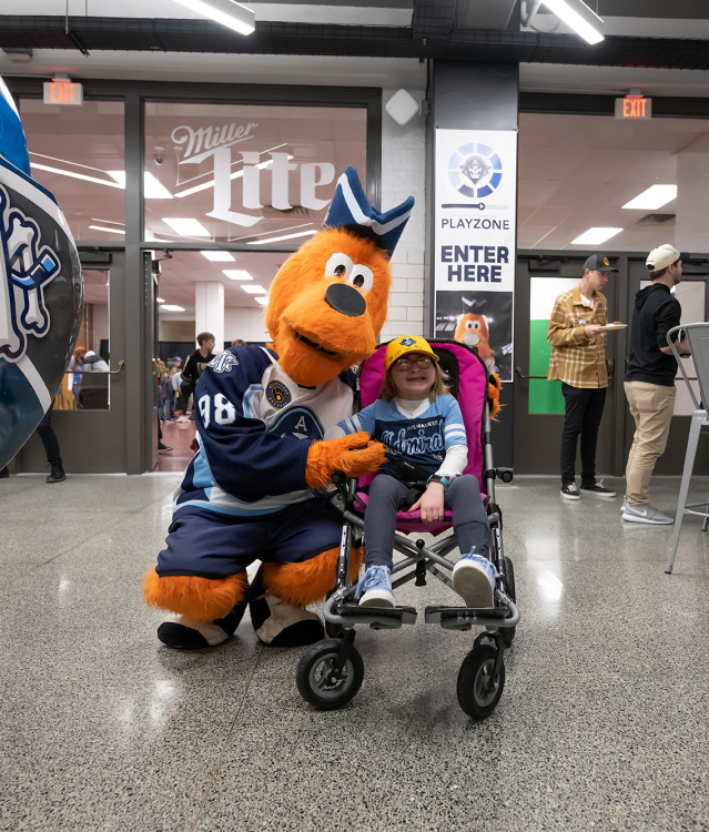 The Milwaukee Admirals mascot, Roscoe, with a young fan in a wheelchair.