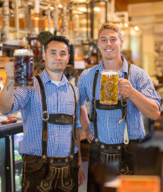 Two men in lederhosen holding liter steins of beer at the Bavarian Bierhaus