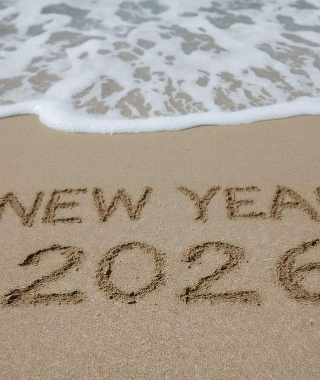 "New Year 2026" written in the sand as the ocean tide comes in.