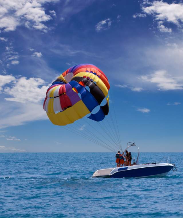 A small boat with a colorful parachute in tow.