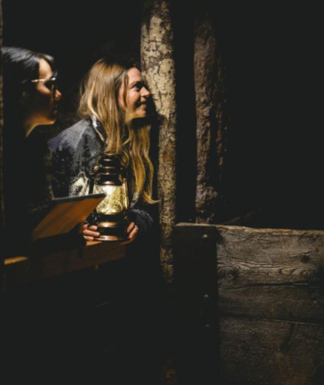 Two people with a lantern looking at a cave wall in the Nanaimo Museum.