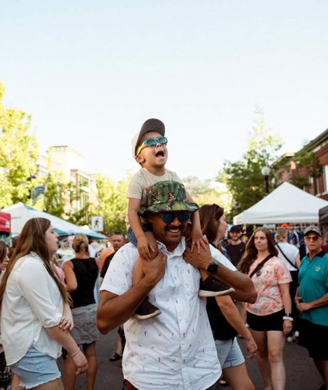 A Dad holding his kid on his shoulders in a crowd.