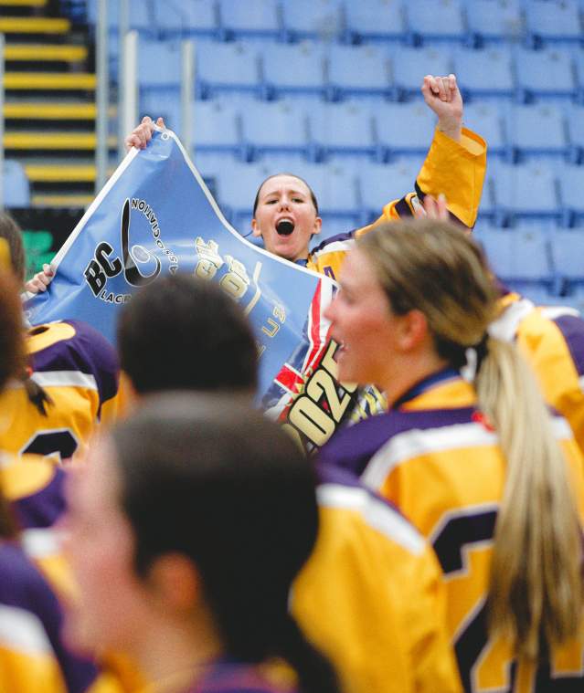 Women's lacrosse celebrating winning holding a banner.