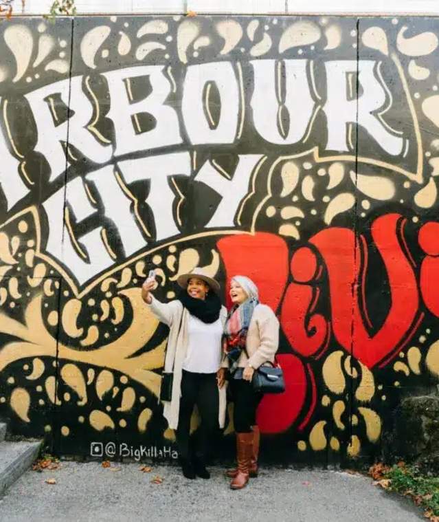 People taking a selfie at a mural.