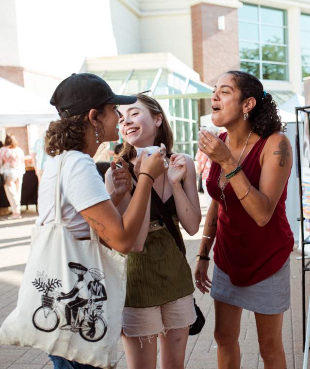 Three people enjoying a farmers market.