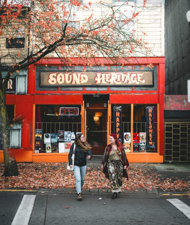 Two people walking outside of Sound Heritage on Victoria Crescent