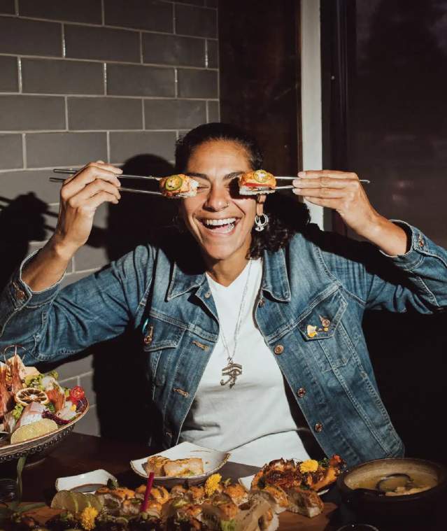 A person using chopsticks to hold sushi up to their eyes.