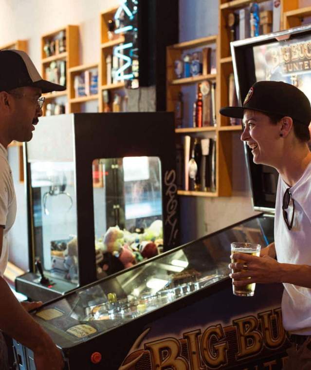 Two men playing pinball.