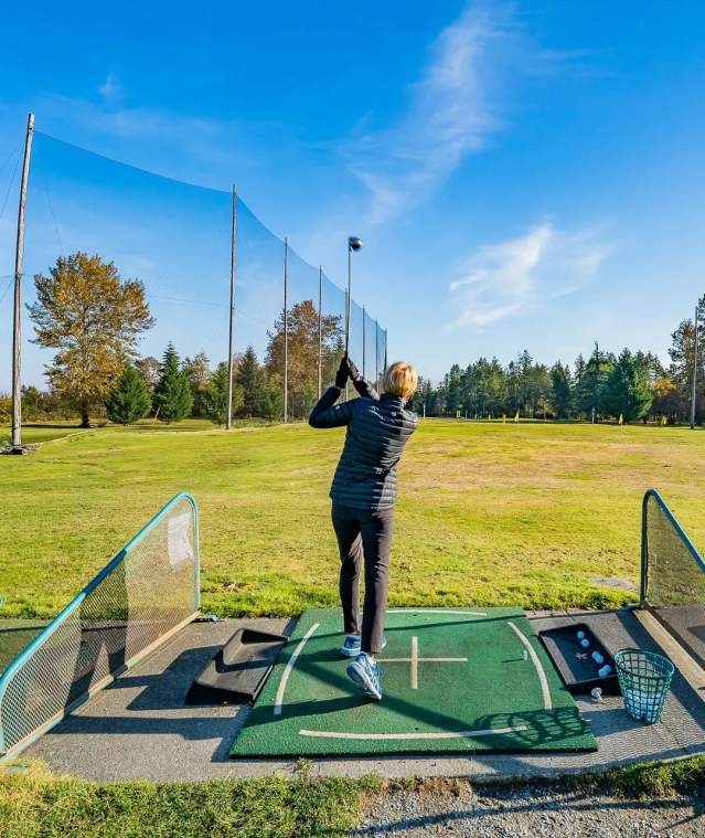 A person hitting a golf ball from a driving range.