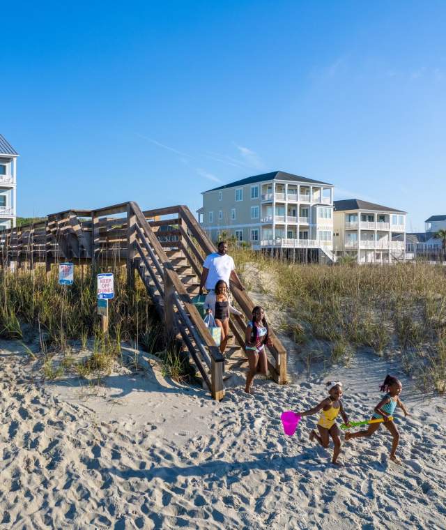 A family walking to the beach over the dunes