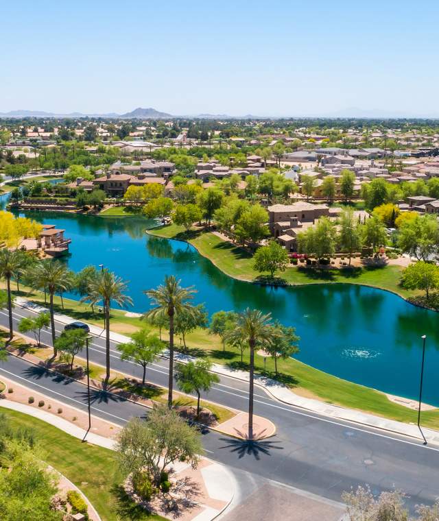 aerial view of residential community with lush landscaping and neighborhood lake surrounded by homes