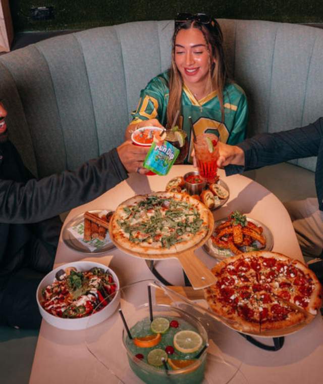 Groups of friends sitting at a table enjoying cocktails and food.