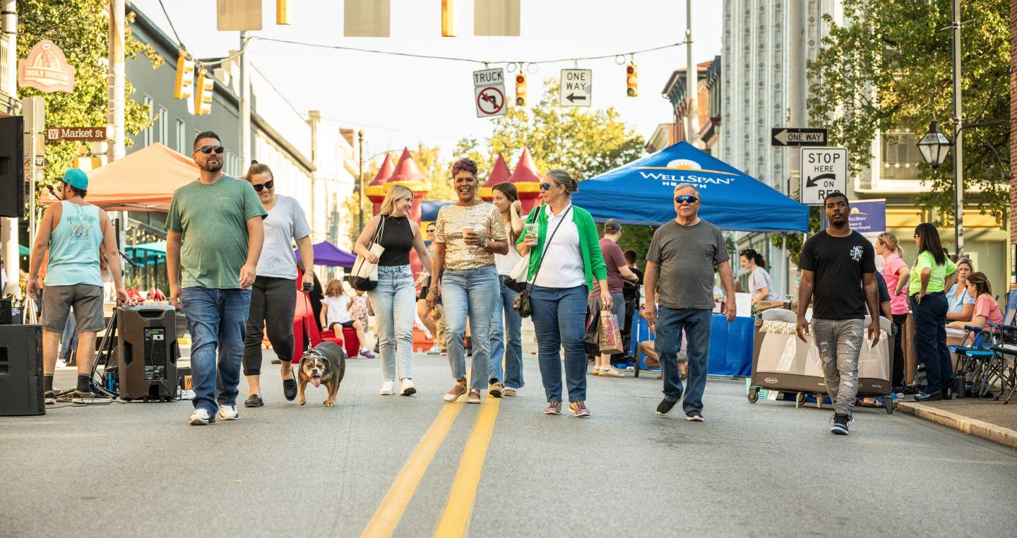 A group of people walking down the street enjoying York City's First Friday monthly celebration