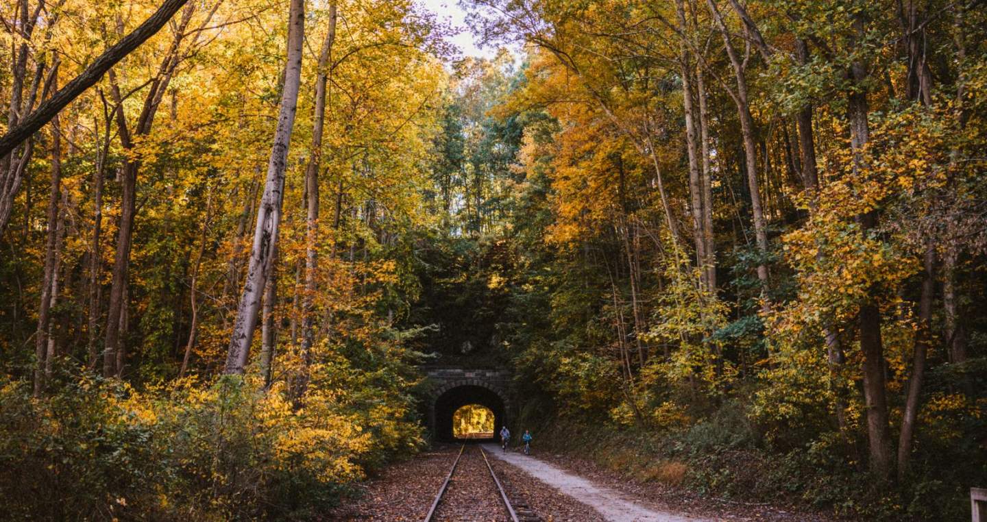 A couple bikes through the historic Howard Tunnel on the rail trail during autumn