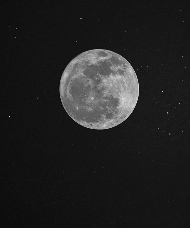 A detailed black and white photo of the full moon surrounded by stars in the night sky.